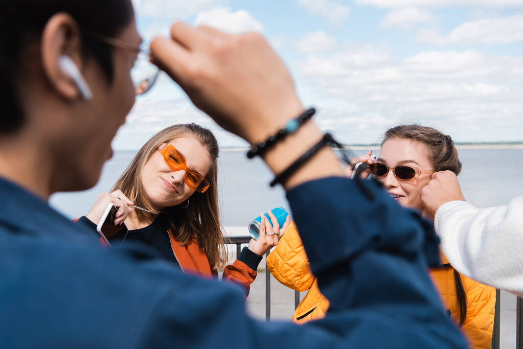 cheerful women in trendy sunglasses looking at man on blurred foreground - Photo, Image