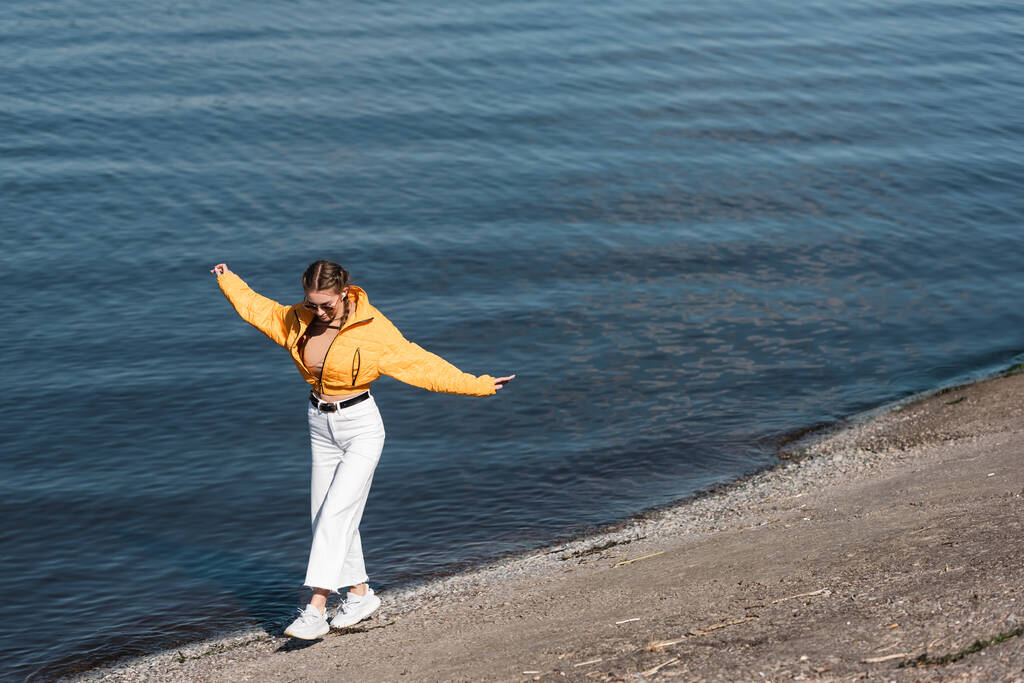 täyspitkä tyylikäs nainen ojensi kätensä kävely pitkin joen rannalla - Valokuva, kuva