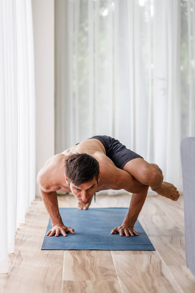 Mladý muž dělá pilates síly nebo jóga cvičení po ránu. Svalnatý muž cvičí doma jógu s potem - Fotografie, Obrázek
