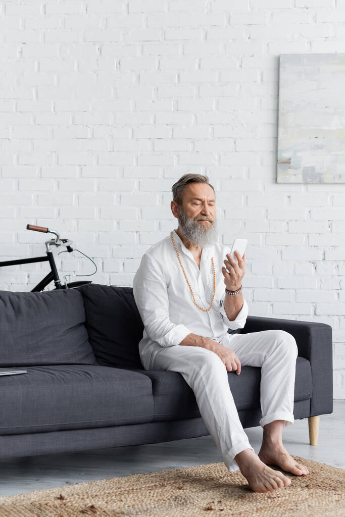 Barfuß-Guru mit Handy auf Couch zu Hause - Foto, Bild