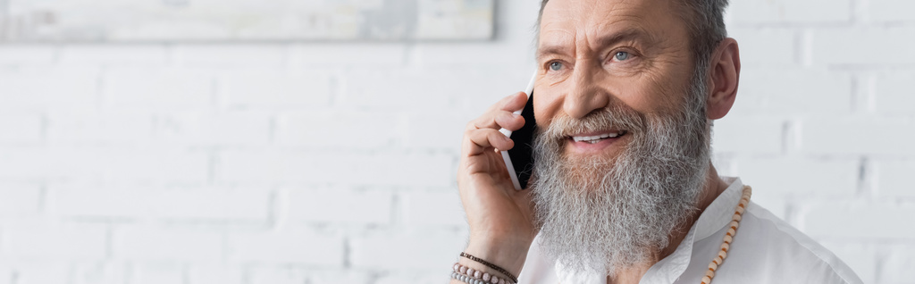 mosolygós szakállas spirituális mentor beszél mobilon otthon, banner - Fotó, kép