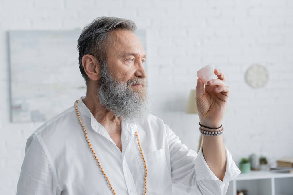 maestro espiritual sénior en pulseras de cuentas meditando con piedra selenita - Foto, imagen