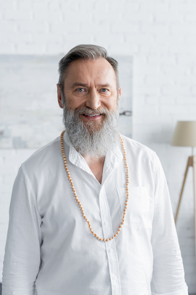 gurú espiritual senior con barba gris sonriendo a la cámara en casa - Foto, imagen