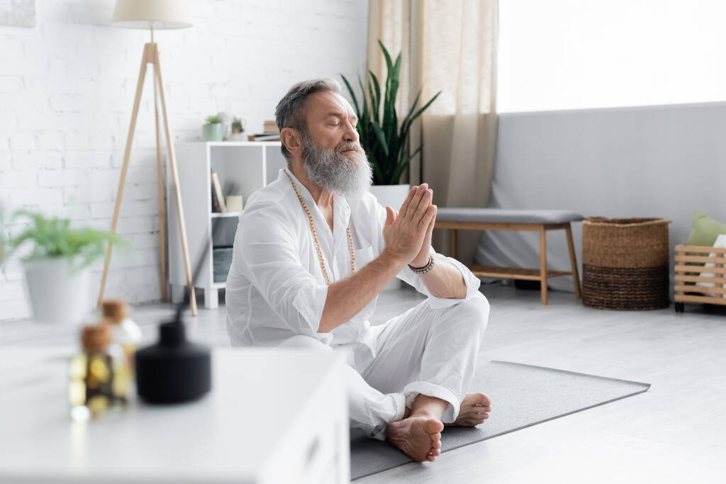 старший майстер йоги, роздумуючи в легкій позі з молитовними руками на розмитому фоні
 - Фото, зображення