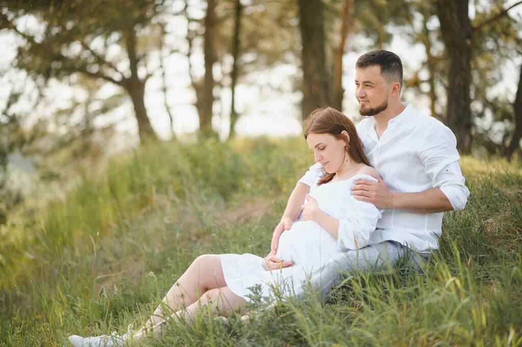 Happy and young pregnant couple hugging in nature. - Photo, Image