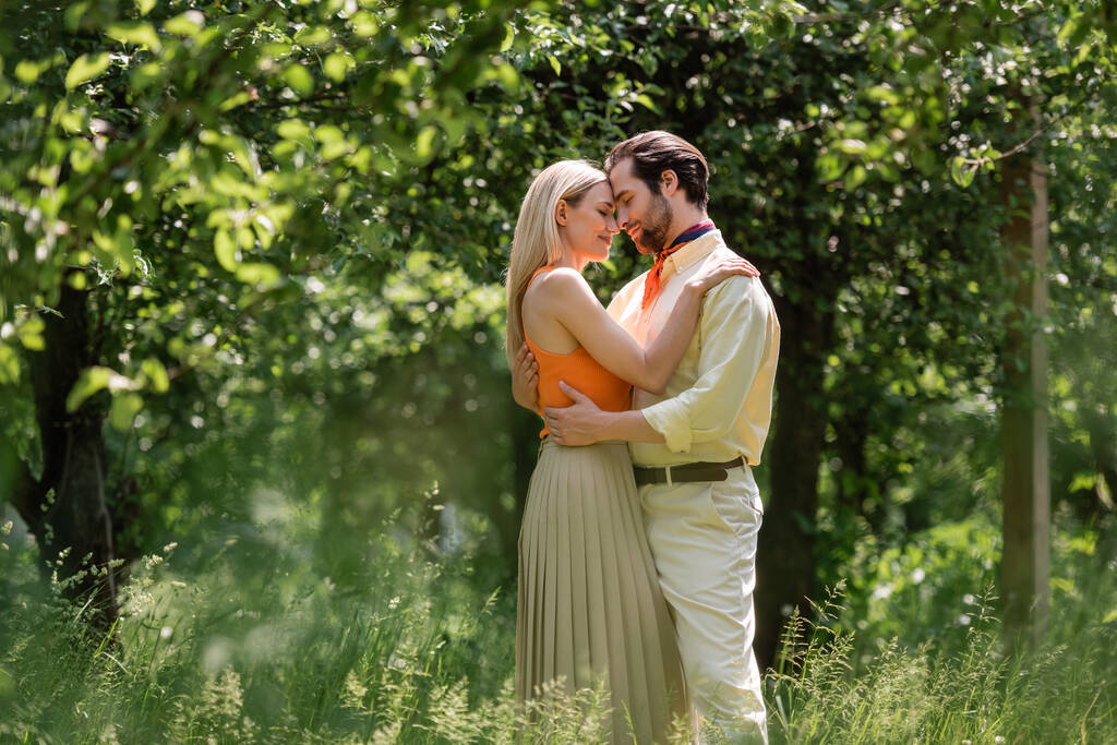 Side view of fashionable couple embracing in summer park  - Photo, Image