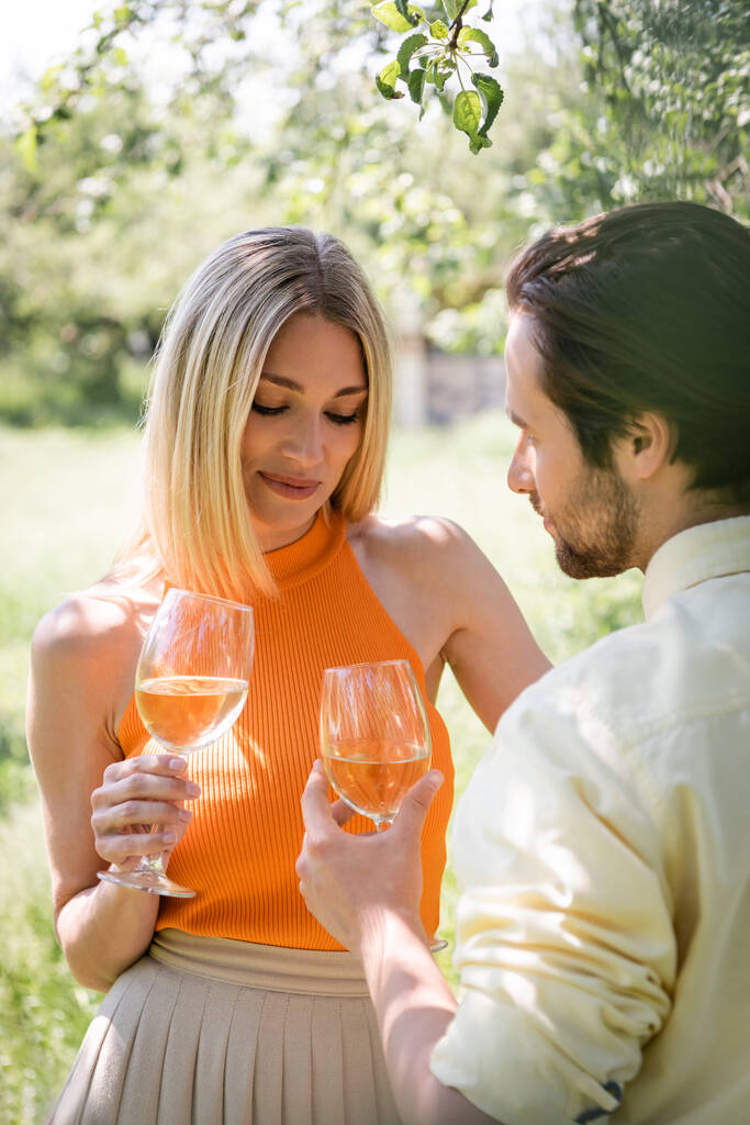 Mulher elegante segurando vinho perto do namorado no parque de verão  - Foto, Imagem