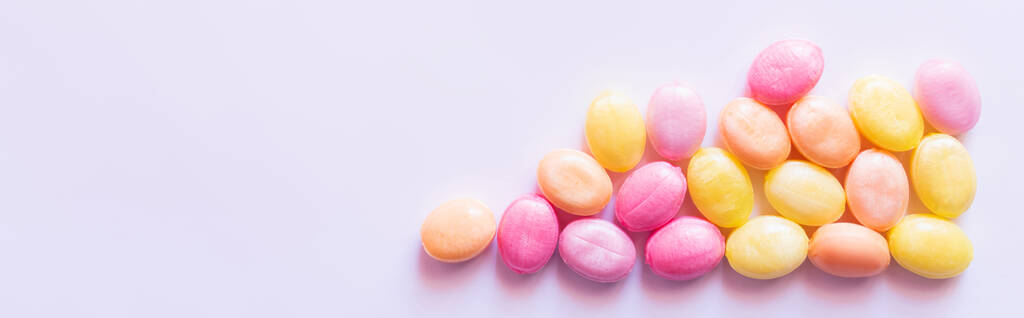 Vista superior de dulces rosados y amarillos sobre fondo blanco, pancarta  - Foto, imagen