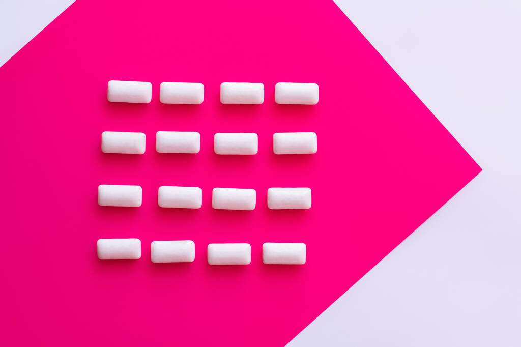 Vlak gelegd met kauwgom op roze en witte achtergrond  - Foto, afbeelding