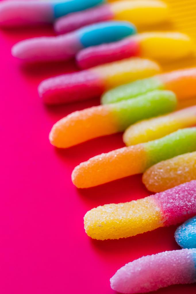 Close up zicht op gelei snoepjes in suiker op roze en gele ondergrond  - Foto, afbeelding