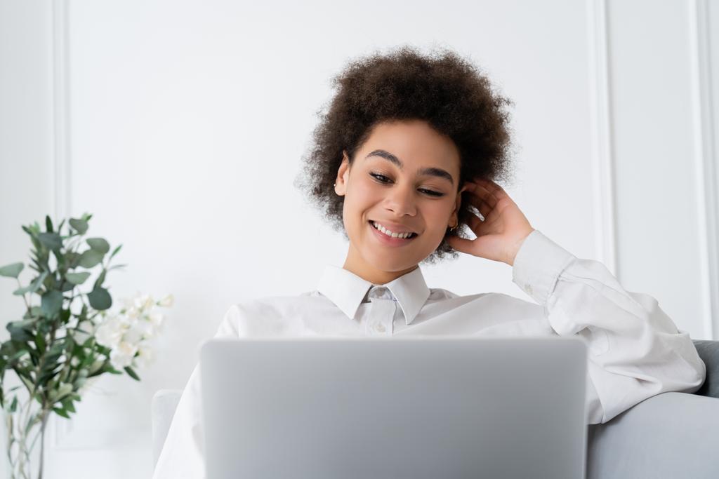 mulher afro-americana positiva usando laptop enquanto trabalhava em casa - Foto, Imagem