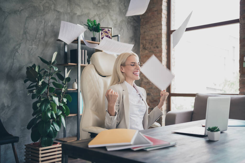 Portrait of overjoyed business lady sit chair throw papers raise fists celebrate attainment achievement workstation indoors. - Photo, Image
