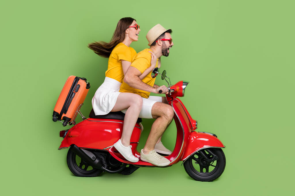 Полноразмерная фотография профиля двух веселых возбужденных партнеров, гоняющих на велосипеде скорость, изолированная на зеленом цветовом фоне. - Фото, изображение