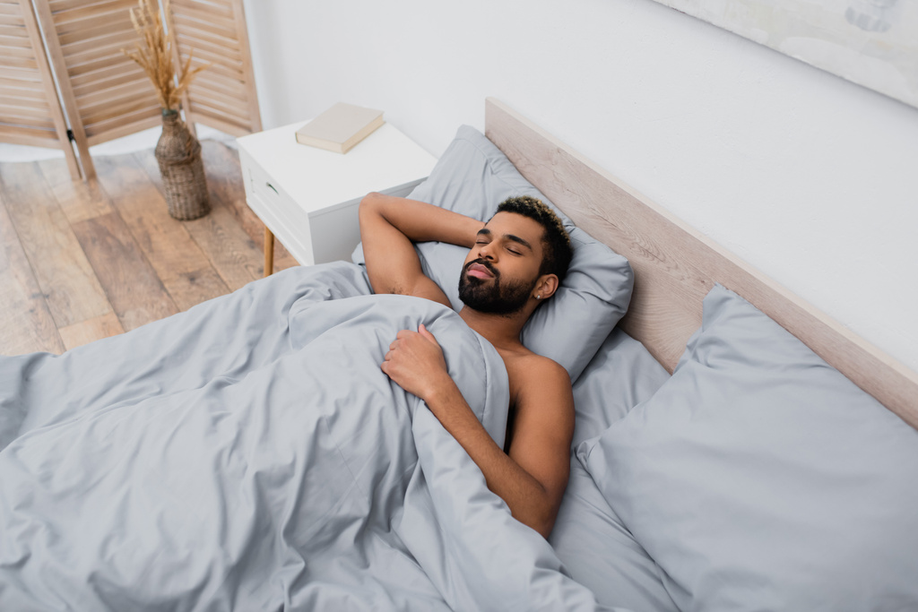 vysoký úhel pohledu na mladé africké Američan muž spí v posteli - Fotografie, Obrázek