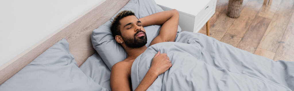 високий кут зору молодого афроамериканця, який спить у ліжку, банер
 - Фото, зображення