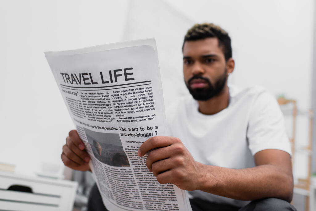 Ciddi bir Afrikalı Amerikalı sakallı adam seyahat gazetesi okuyor. - Fotoğraf, Görsel