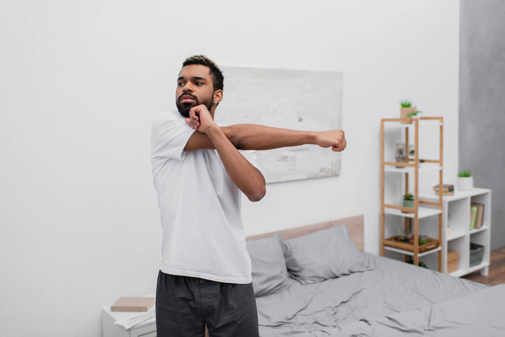 ベッドルームで朝の運動をするアフリカ系アメリカ人の髭  - 写真・画像