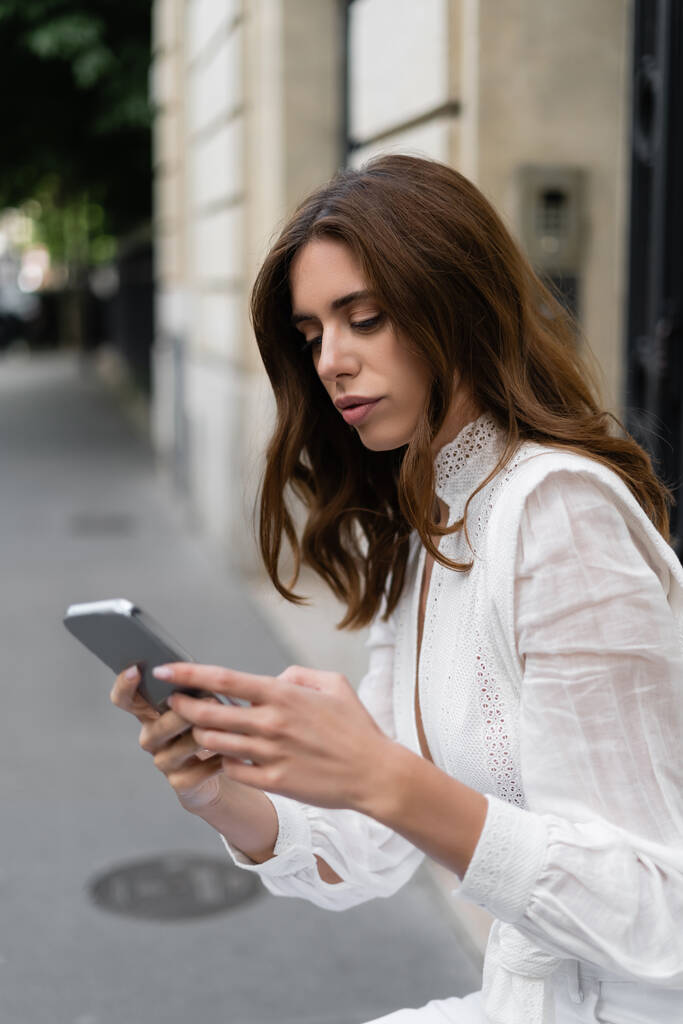 Turista en blusa con teléfono móvil en la calle urbana de París  - Foto, Imagen