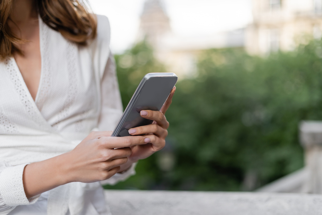Rajatut näkymä tyylikäs nainen käyttää älypuhelinta kadulla Pariisissa  - Valokuva, kuva