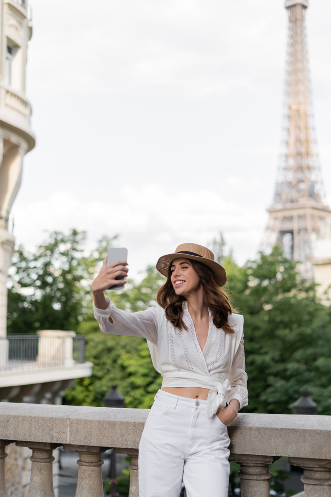 Усміхаючись, туристи роблять самовіддані з Ейфелевою вежею на задньому плані в Парижі.  - Фото, зображення