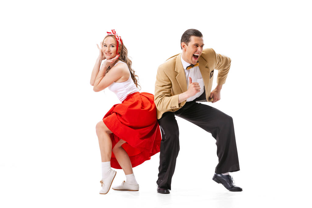 Casal expressivo de dançarinos em trajes de estilo retro vintage dançando dança social isolada em fundo branco. Tradições atemporais, anos 60, estilo de moda americano dos anos 70. Dançarinos parecem animados - Foto, Imagem