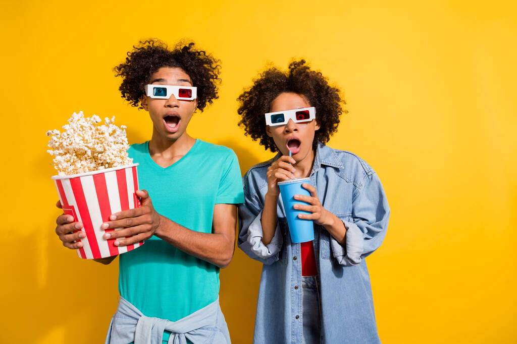 Photo of shocked afro american people couple wear 3d glasses movie pop corn fly drink isolated on yellow color background. - Photo, Image