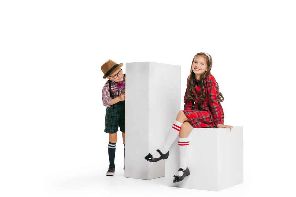 Γνωστοποίηση. Πορτρέτο του μικρού αγοριού και του κοριτσιού, γοητευτικό παιδιά ρετρό στυλ στολή, μόδα της δεκαετίας του '70, 80 χρόνια απομονώνονται σε λευκό φόντο στούντιο με αντίγραφο χώρο για διαφήμιση. - Φωτογραφία, εικόνα