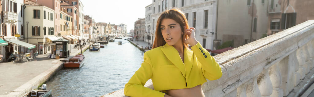 stijlvolle vrouw in geel gewas jas weg te kijken op brug over Venetiaans Grand Canal, banner - Foto, afbeelding