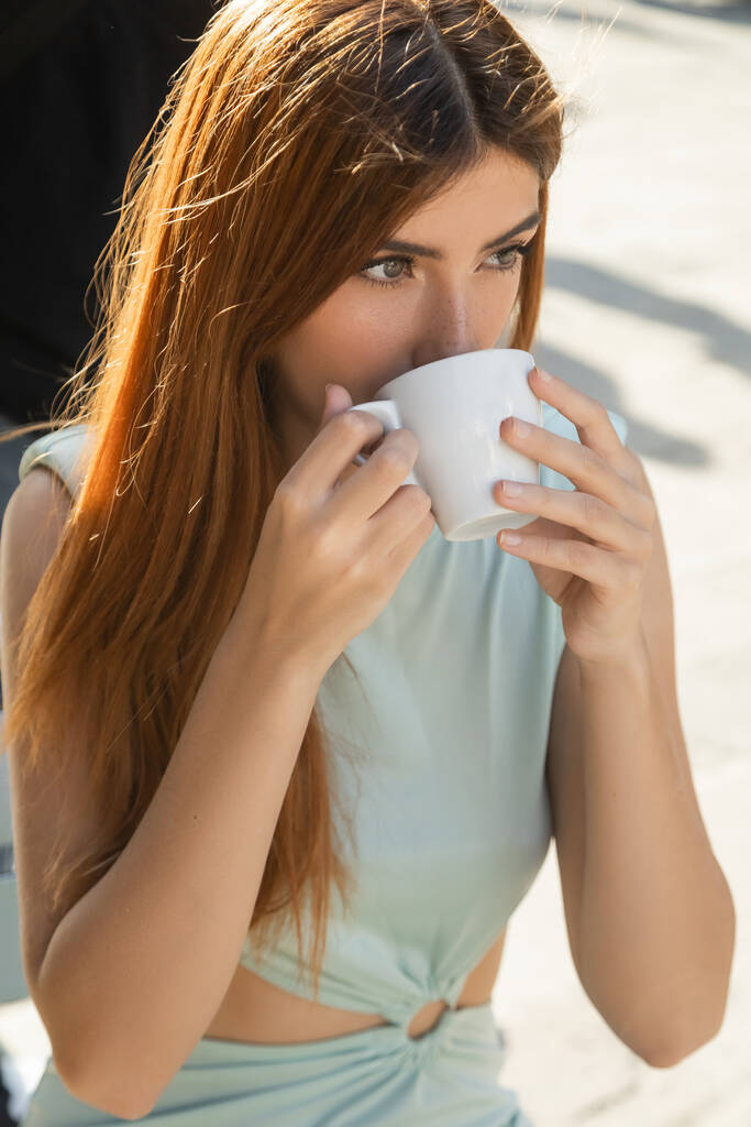 γυναίκα με κόκκινα μαλλιά κοιτάζει μακριά, ενώ πίνοντας καφέ στη Βενετία - Φωτογραφία, εικόνα