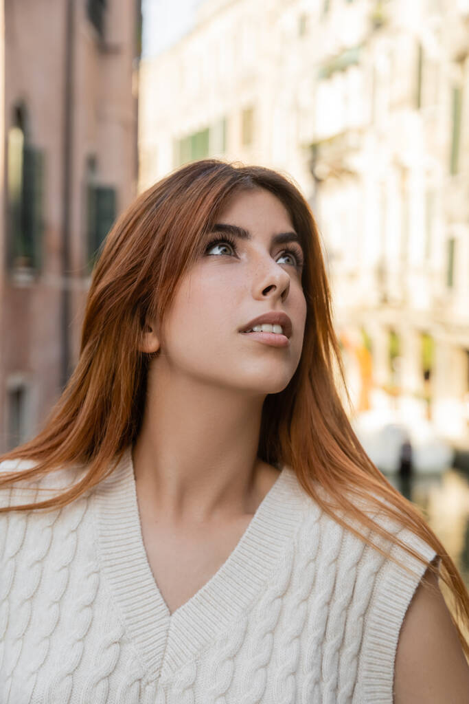 Venedik 'teki bulanık arka plana bakan kızıl saçlı genç kadının portresi. - Fotoğraf, Görsel