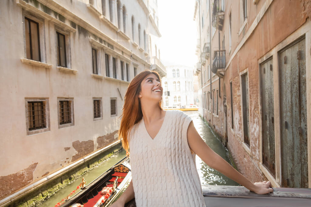 happy redhead woman in summer knitwear looking at medieval buildings in Venice - Photo, Image