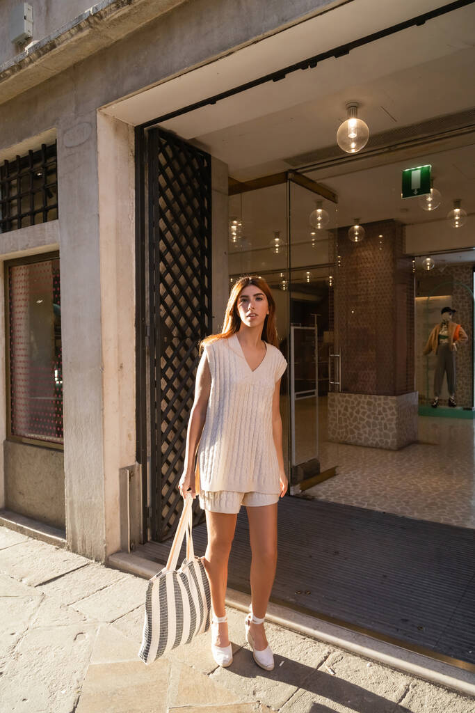 Venedik 'teki binanın girişine yakın çizgili çantalı modaya uygun bir kadın. - Fotoğraf, Görsel