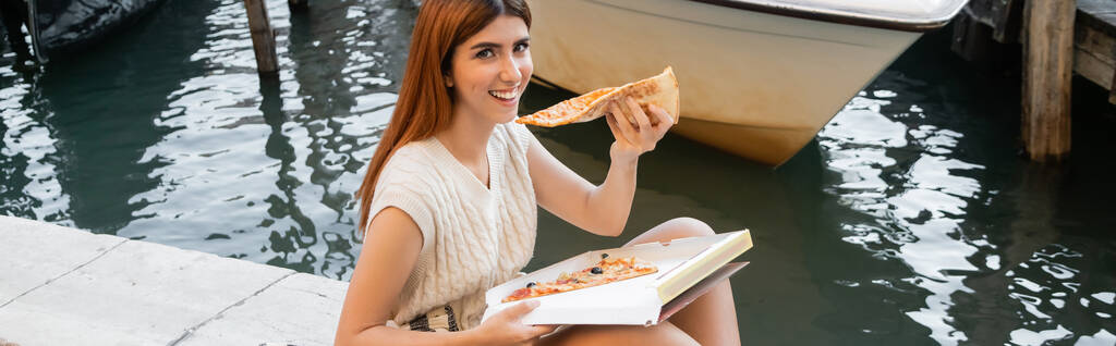 happy young woman with delicious pizza looking at camera in Venice, banner - Photo, Image