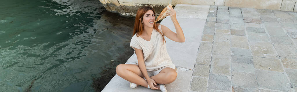vysoký úhel pohledu na šťastnou ženu jíst lahodnou pizzu během víkendu v Benátkách, banner - Fotografie, Obrázek