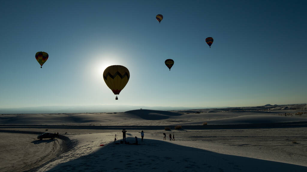Una vista impresionante de la gente mirando los globos de aire caliente en un cielo azul claro - Foto, Imagen