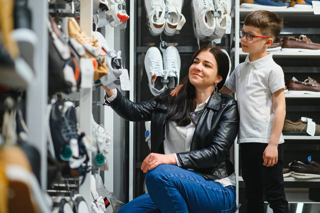 Mother with children choosing shoes in kids store. - Photo, Image