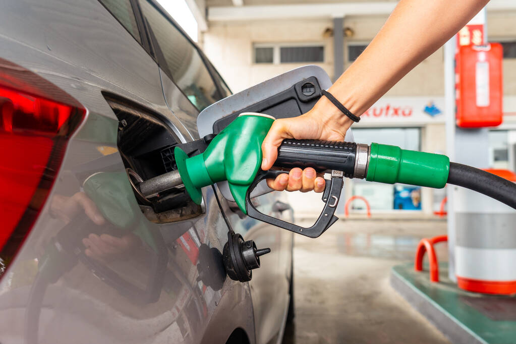 Жінка дозаправляє бензин на АЗС в умовах паливної кризи з високими цінами
 - Фото, зображення