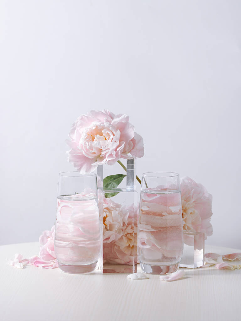 Egy függőleges lövés gyönyörű rózsaszín bazsarózsa virágok egy üveg váza egy fehér háttér - Fotó, kép