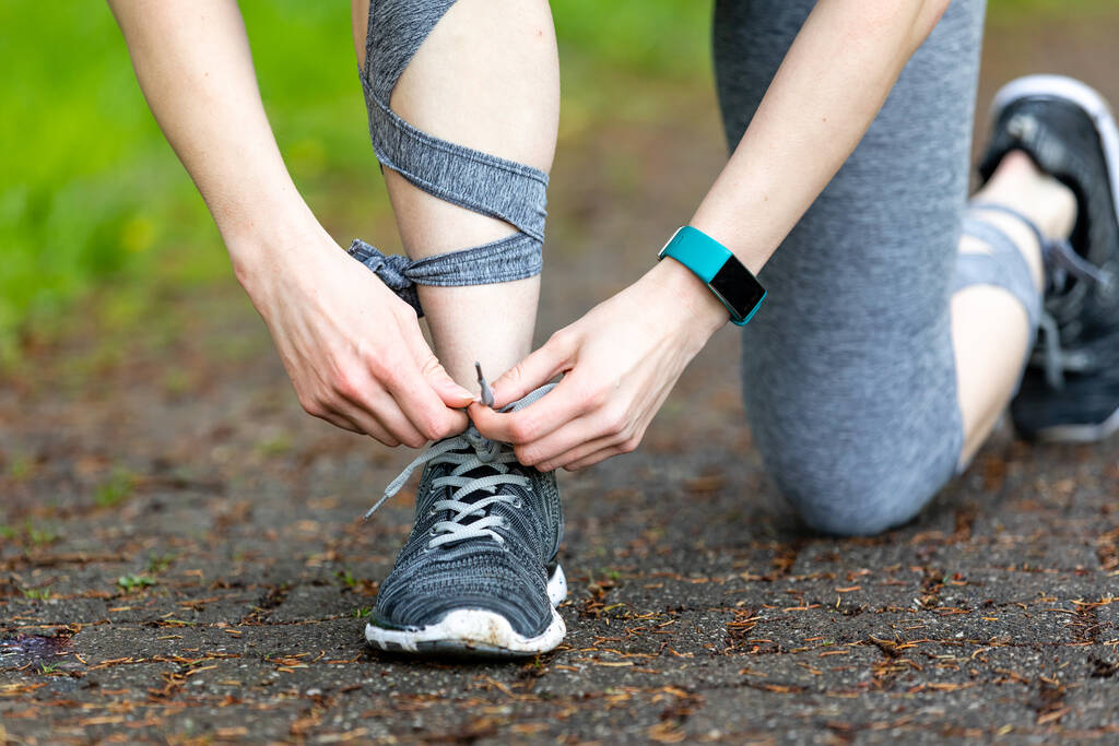 A closeup shot of a woman doing fitness exercises and tying her shoelaces - Photo, Image