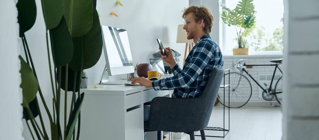 Αυτοπεποίθηση των νέων που χρησιμοποιούν τεχνολογίες ενώ κάθονται στο χώρο εργασίας τους στο σπίτι - Φωτογραφία, εικόνα