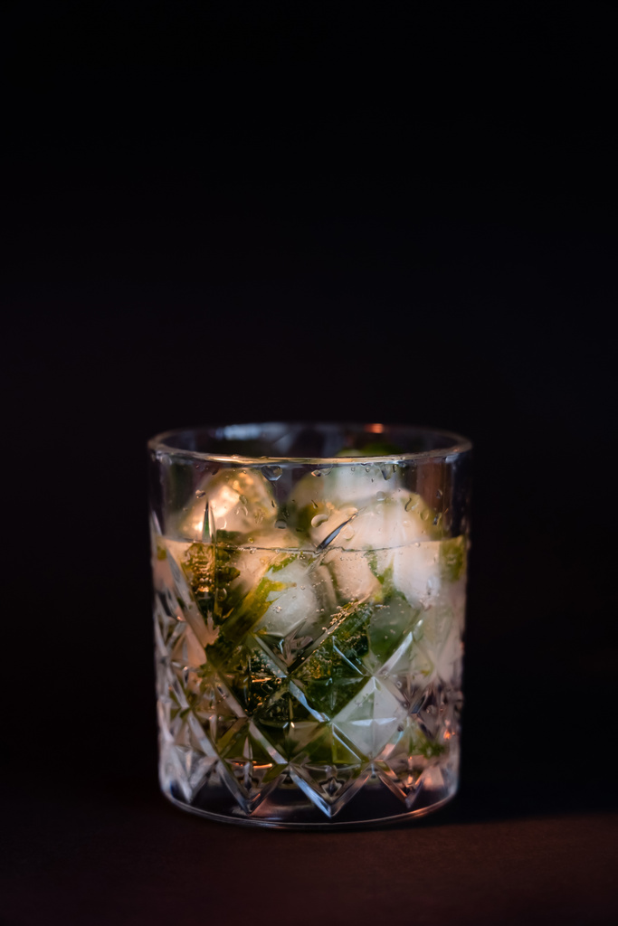koel geslepen glas met rum en ijsblokjes geïsoleerd op zwart  - Foto, afbeelding