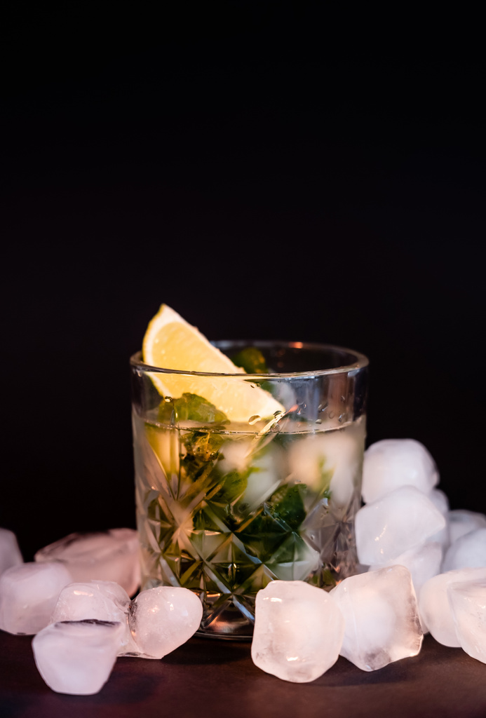 cool faceted glass with mojito near ice cubes on black  - Foto, imagen