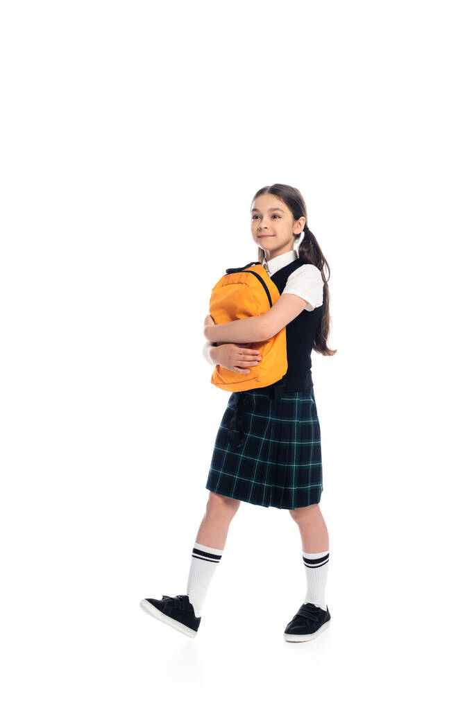 Школьница в полный рост держит рюкзак и ходит на белом фоне - Фото, изображение