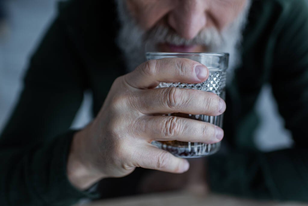 levágott kilátás idős férfi iszik whisky miközben kezében üveg  - Fotó, kép