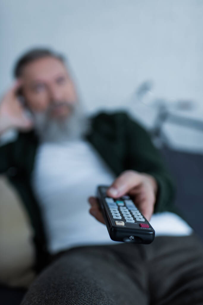 blurred senior man holding remote controller while watching tv  - Photo, Image