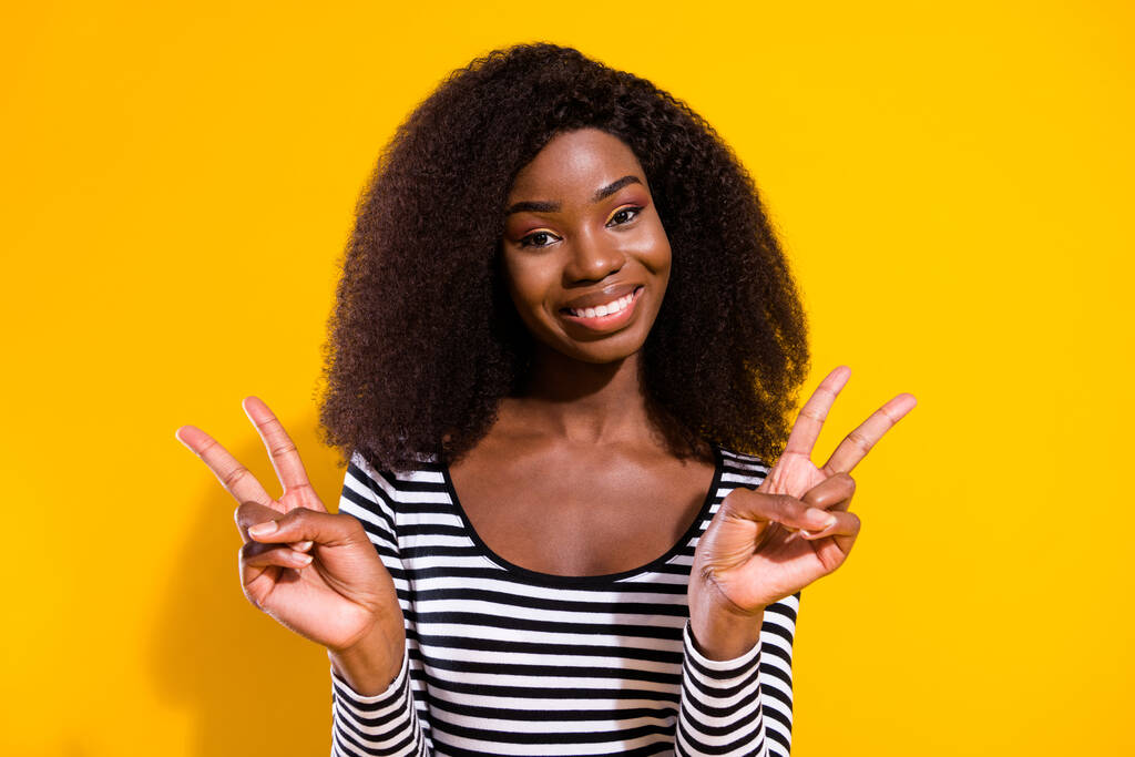 Foto ritratto di donna riccia prendere selfie sorridente mostrando v-segno gesto di pace entrambe le mani isolato vivido colore giallo sfondo. - Foto, immagini