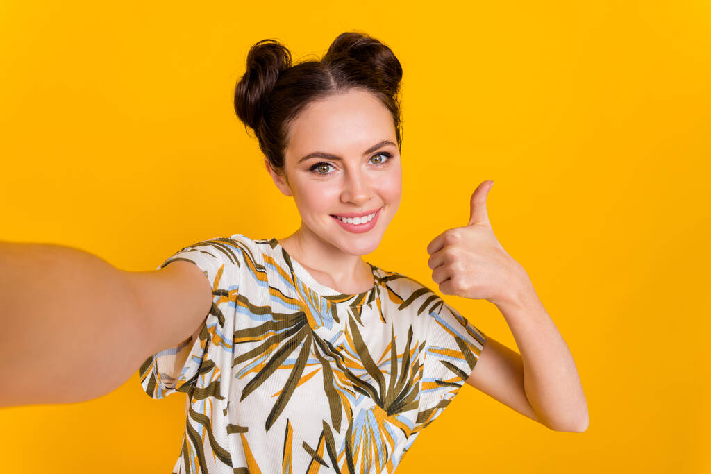 Foto van glanzende mooie vrouw dragen print t-shirt opname video tonen duim omhoog geïsoleerde gele kleur achtergrond. - Foto, afbeelding
