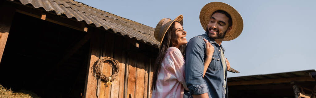 счастливая женщина в соломенной шляпе обнимает бородатого мужа возле деревянного сарая, плакат - Фото, изображение