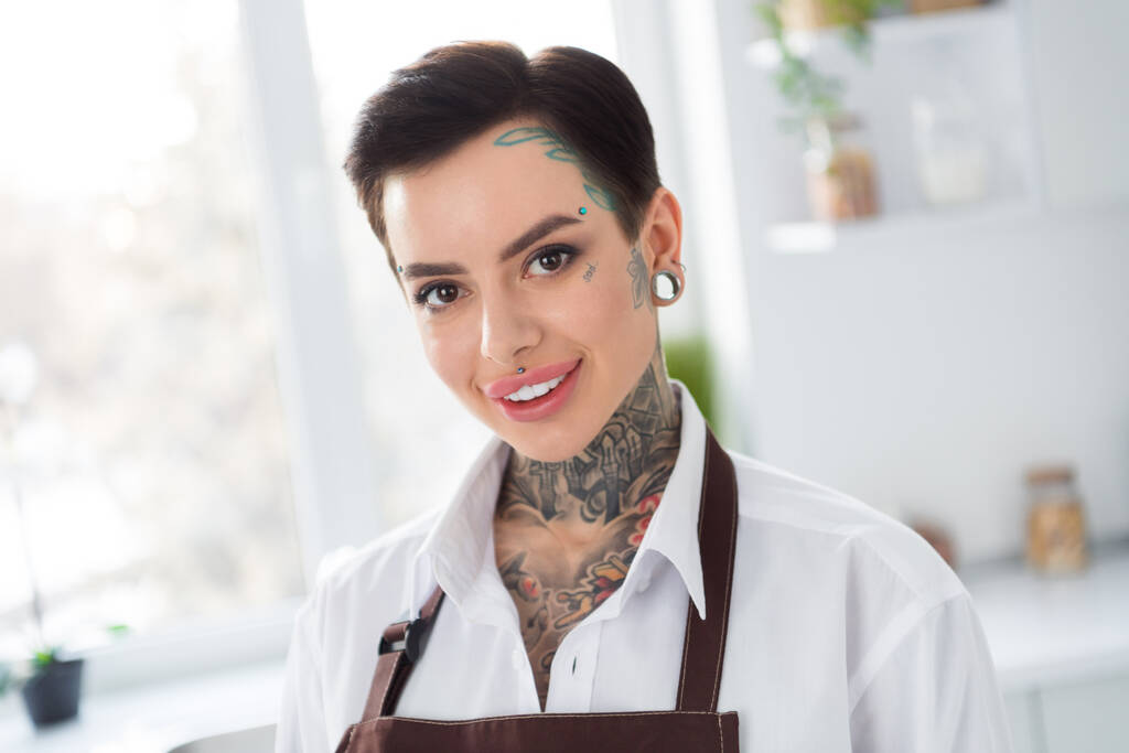 Portret van jonge schattige dame met piercing en tatoeage werken als chef-kok in restaurant maken heerlijke lekkere gerechten. - Foto, afbeelding
