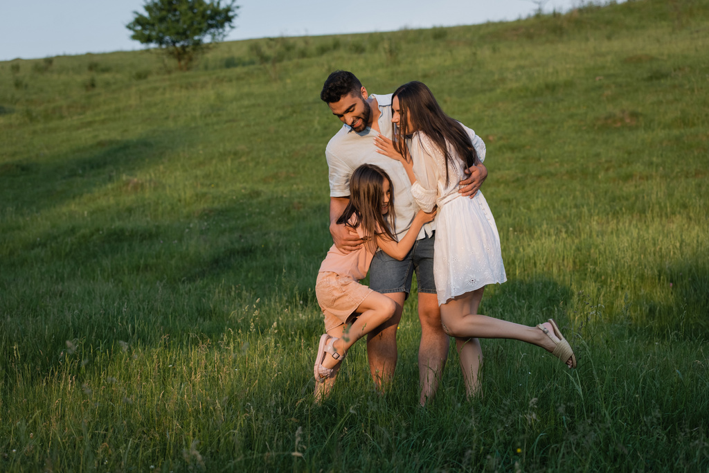 πλήρης διάρκεια ευτυχισμένη οικογένεια αγκαλιάζει στο πεδίο την ημέρα του καλοκαιριού - Φωτογραφία, εικόνα